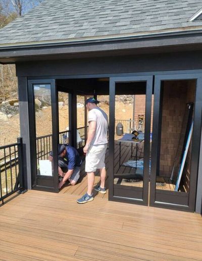 two men installing glass doors on an enclosed porch