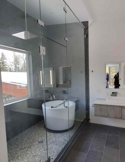 modern primary bathroom with floor to ceiling glass